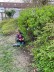 Ein Kind sitzt neben dem Busch, wo es ein Osterei gefunden hat.