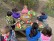Kinder sitzen am Picknicktisch und schauen ihre Osterkörbe an.