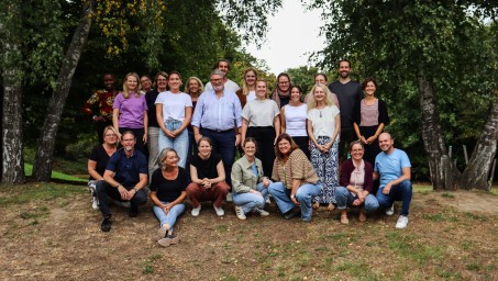 Lehrkräfte des GL-Teams stehen in mehreren Reihen vor Bäumen auf dem Schulhof.