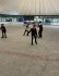 4 Schüler*innen fahren in einer recht leeren Halle Schlittschuh, einer lacht in die Kamera