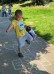 Ein Junge hüpft einbeinig auf einem mit Hüpfekästchen farbig bemalten Weg.