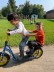 zwei Jungen fahren auf einem Roller und lachen