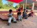 Viele Kinder sitzen vor einem Sandkasten und löffeln Eis