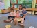 drei Kinder und eine Lehrerin sitzen auf dem Boden uns schauen in verschiedene Bilderbücher