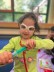 ein Mädchen trägt eine große Brille und ein Stethoskop, sie hält eine Spielzeug-Spritze in der Hand