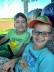 2 Kinder sitzen nebeneinander in einem Reisebus und lachen in die Kamera