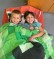 2 Kinder liegen nebeneinander auf einer Matratze und lachen in die Kamera