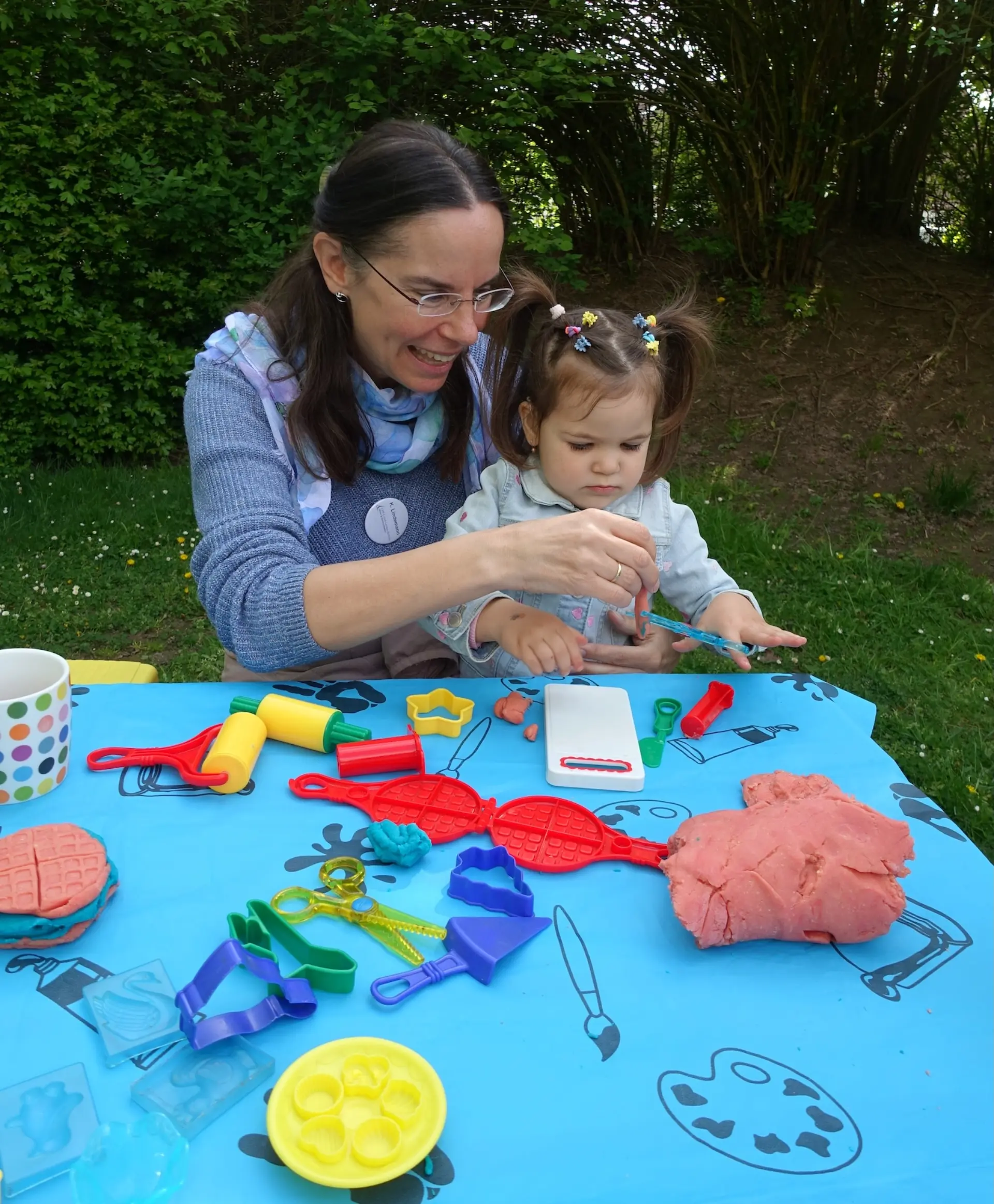 Ein Kind und eine Frühförderin spielen gemeinsam mit Knete