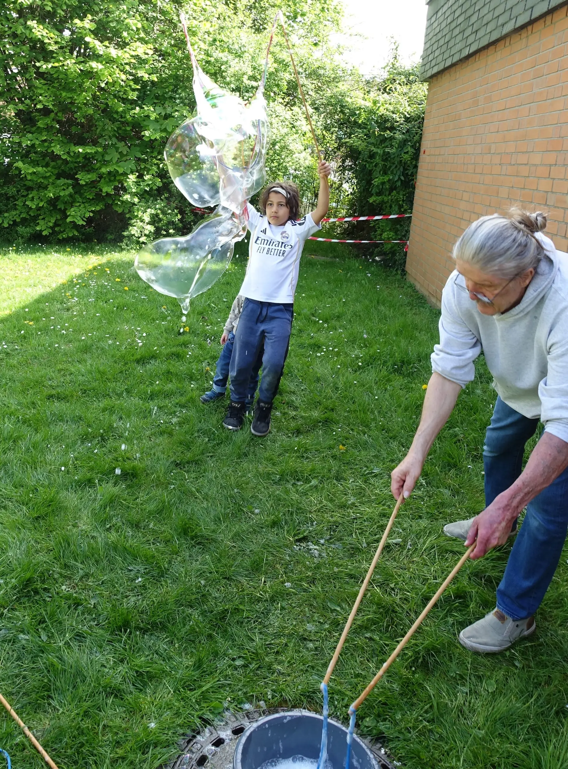 ein Kind und ein Erwachsener spielen mit Riesen-Seifenblasen