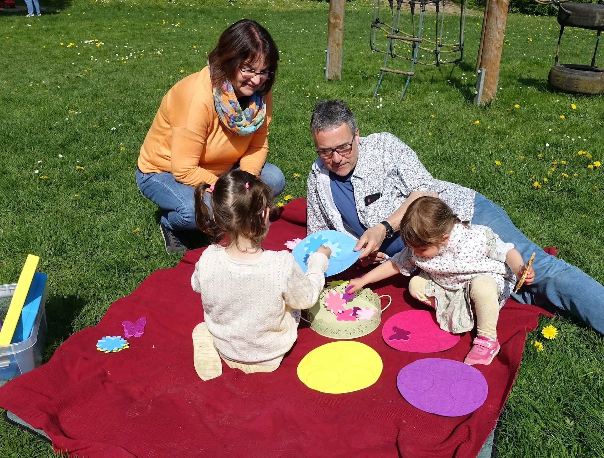 Eine Familie sitzt draußen auf einer Decke und sortiert Blumen