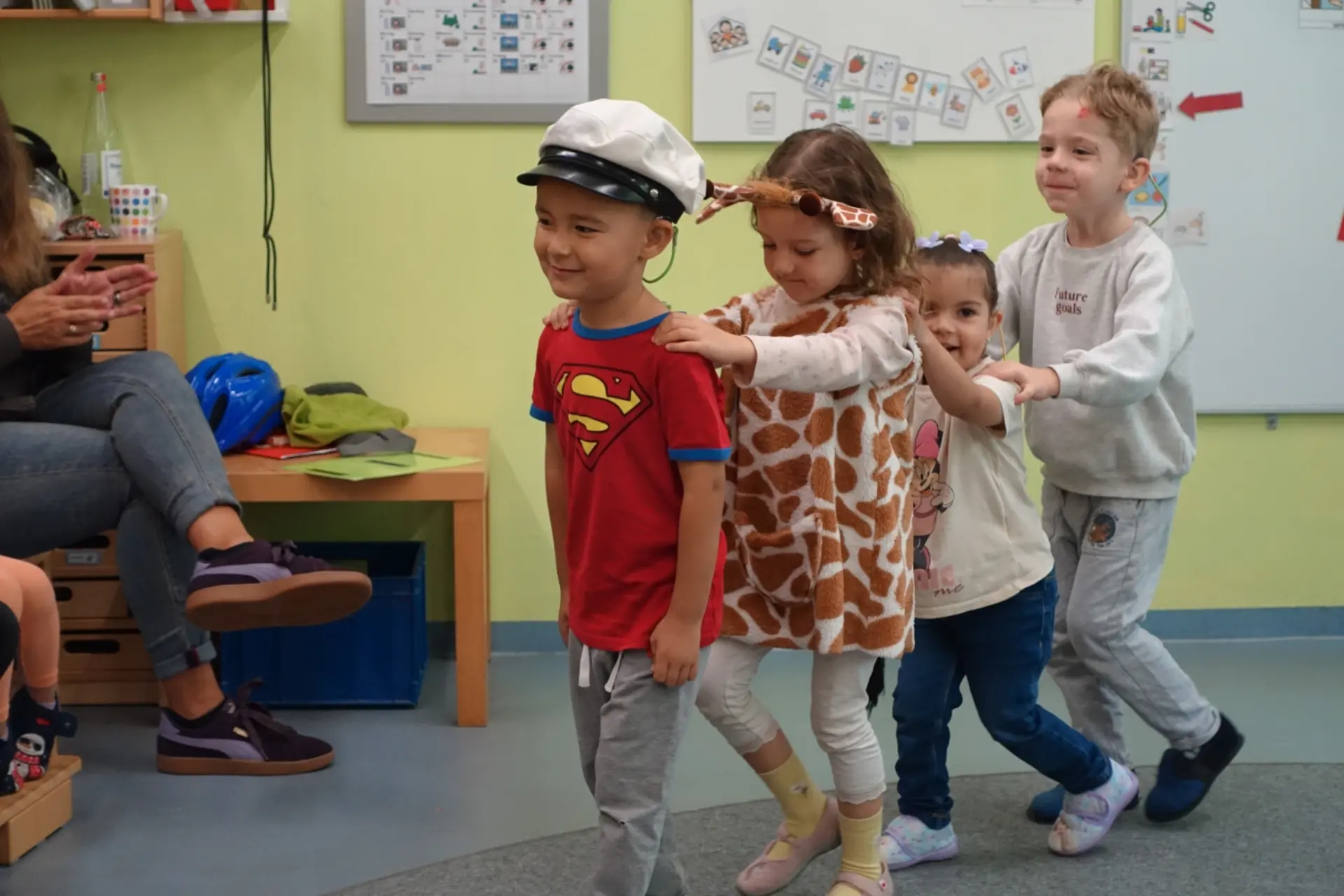 Vier Kinder spielen Eisenbahn und fassen sich an die Schultern