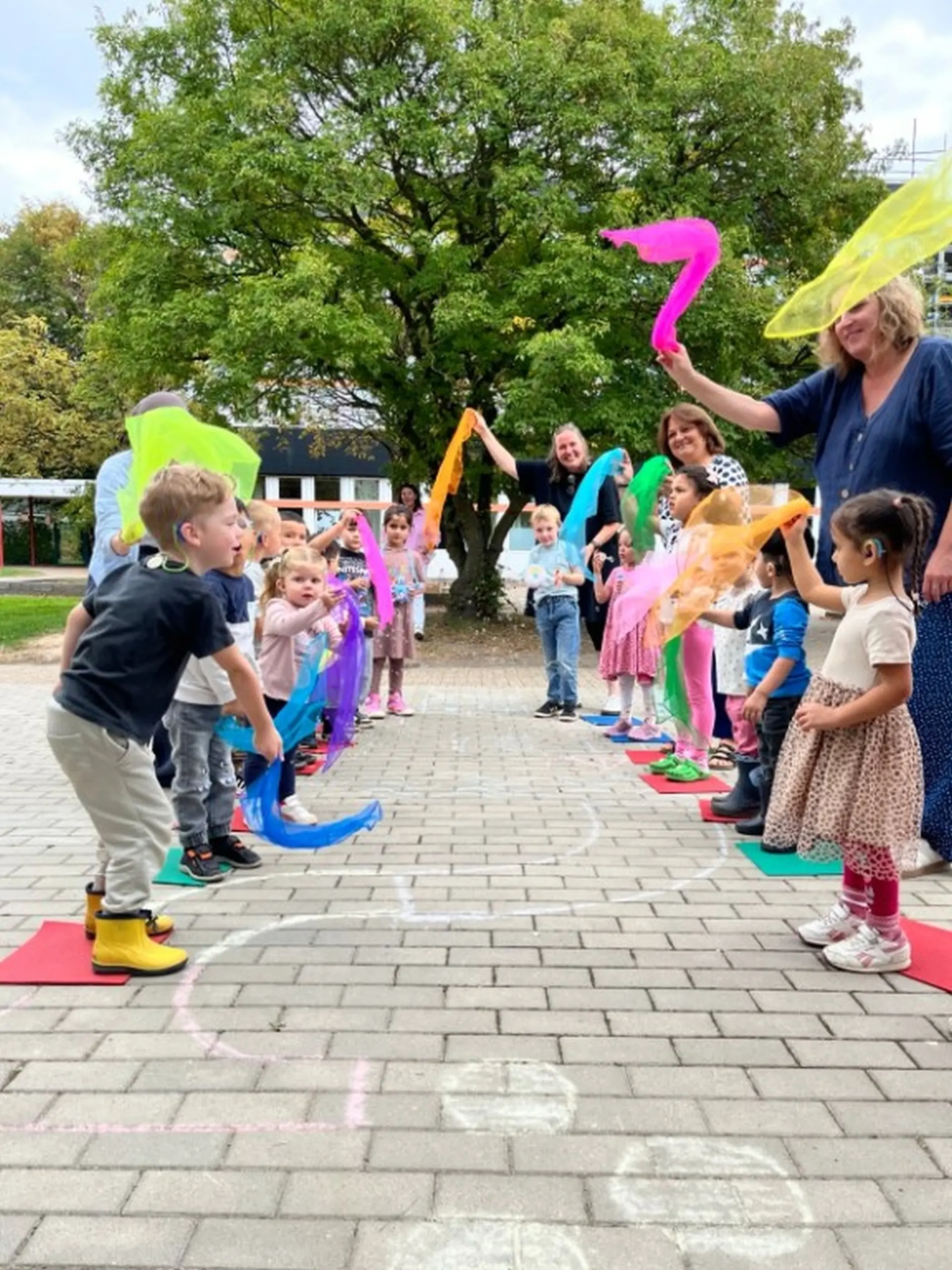 Kinder stehen auf dem Schulhof Spalier und begrüßen die erste Klasse