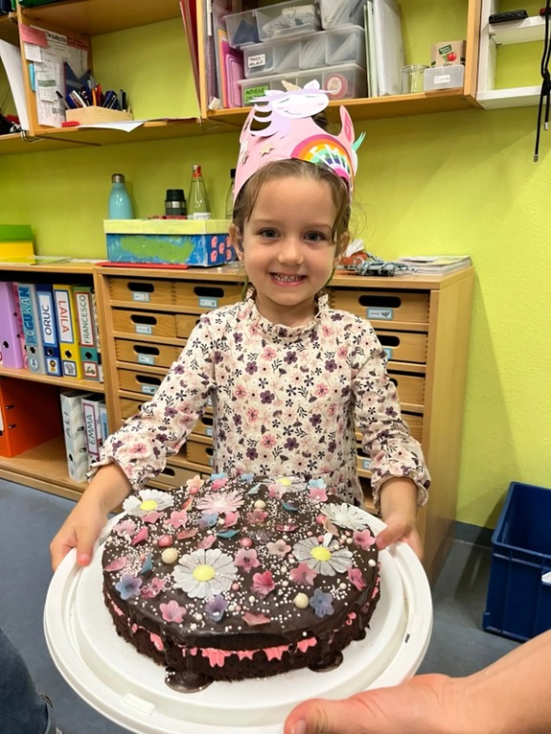 Ein Mädchen hält stolz einen Geburtstagskuchen in die Kamera