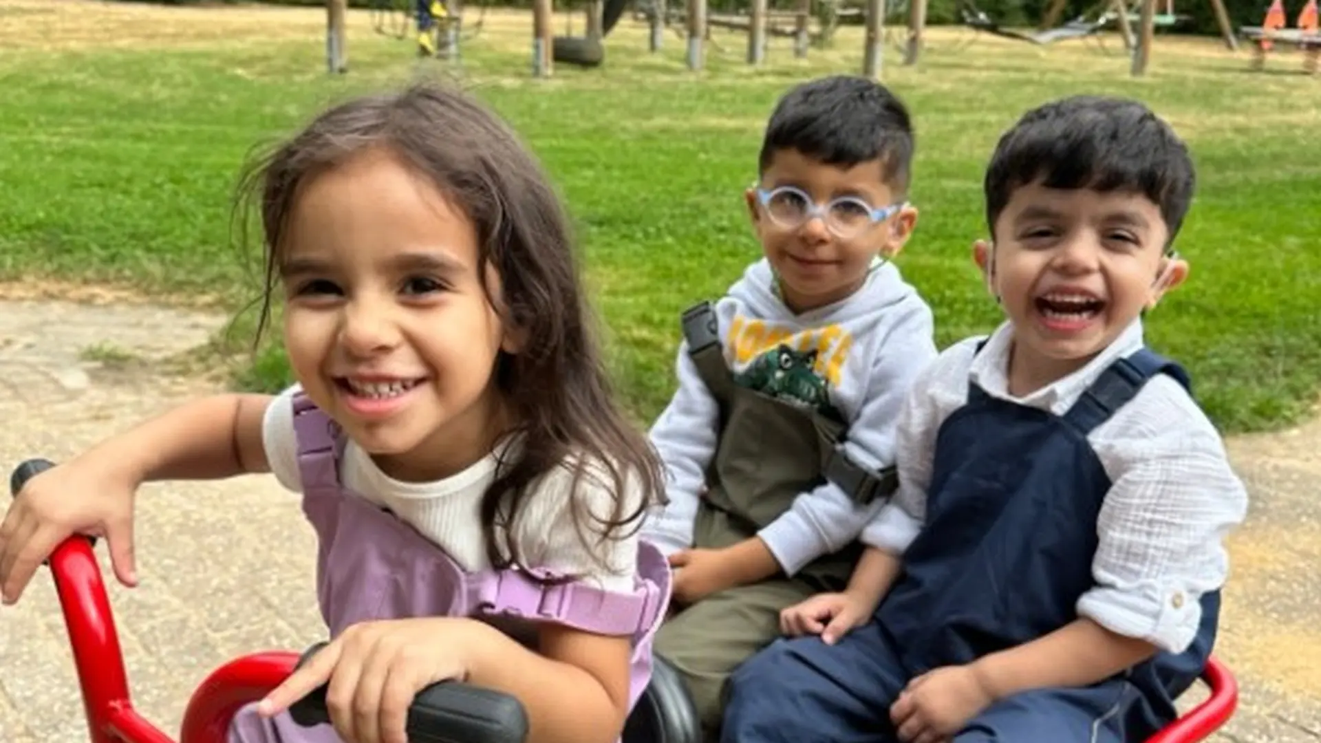 Kinder spielen auf dem Gelände draußen mit einem Spielzeugtaxi