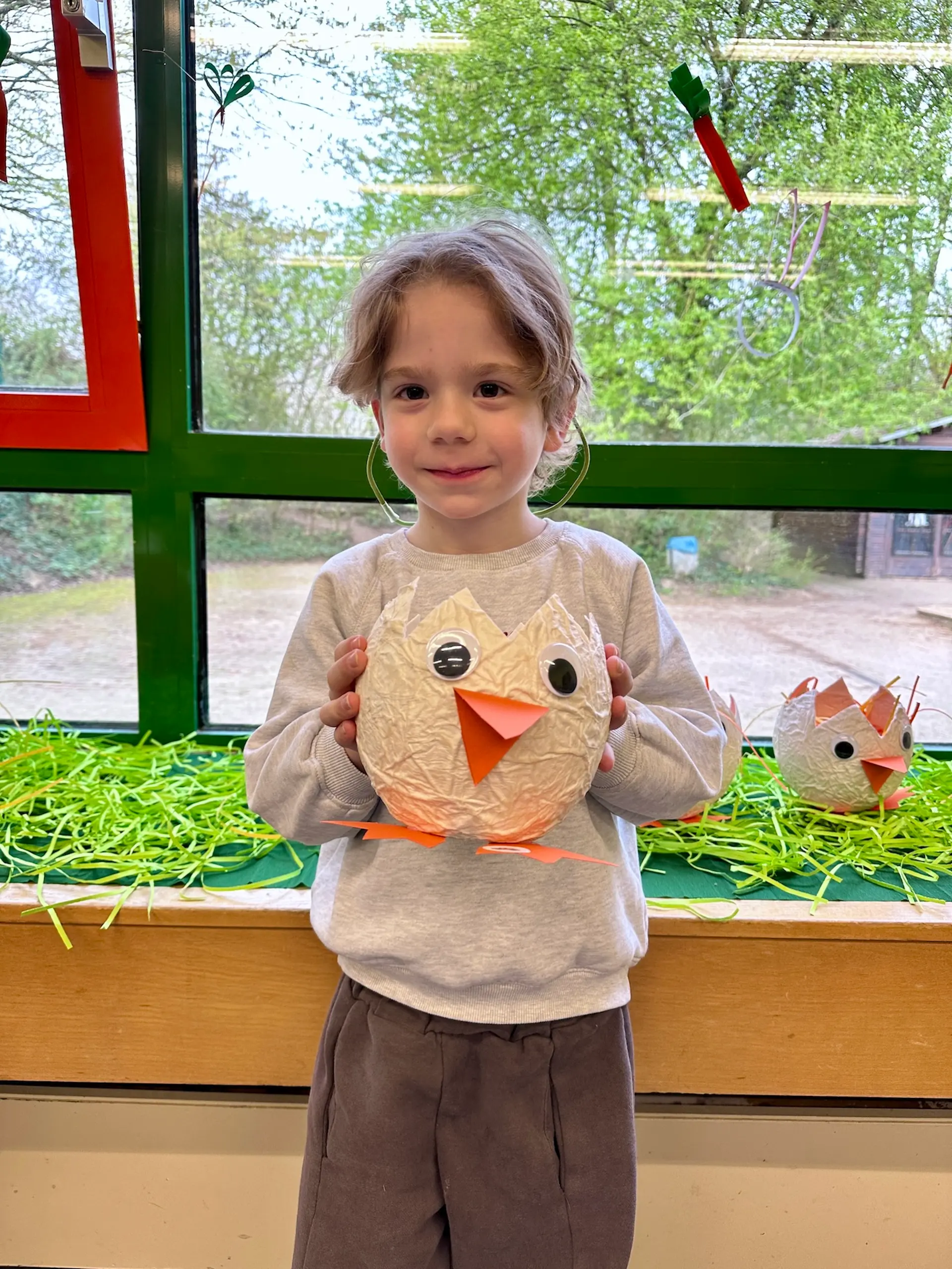 Ein Kind hält ein gebasteltes Osternetz in Form eines Vogels
