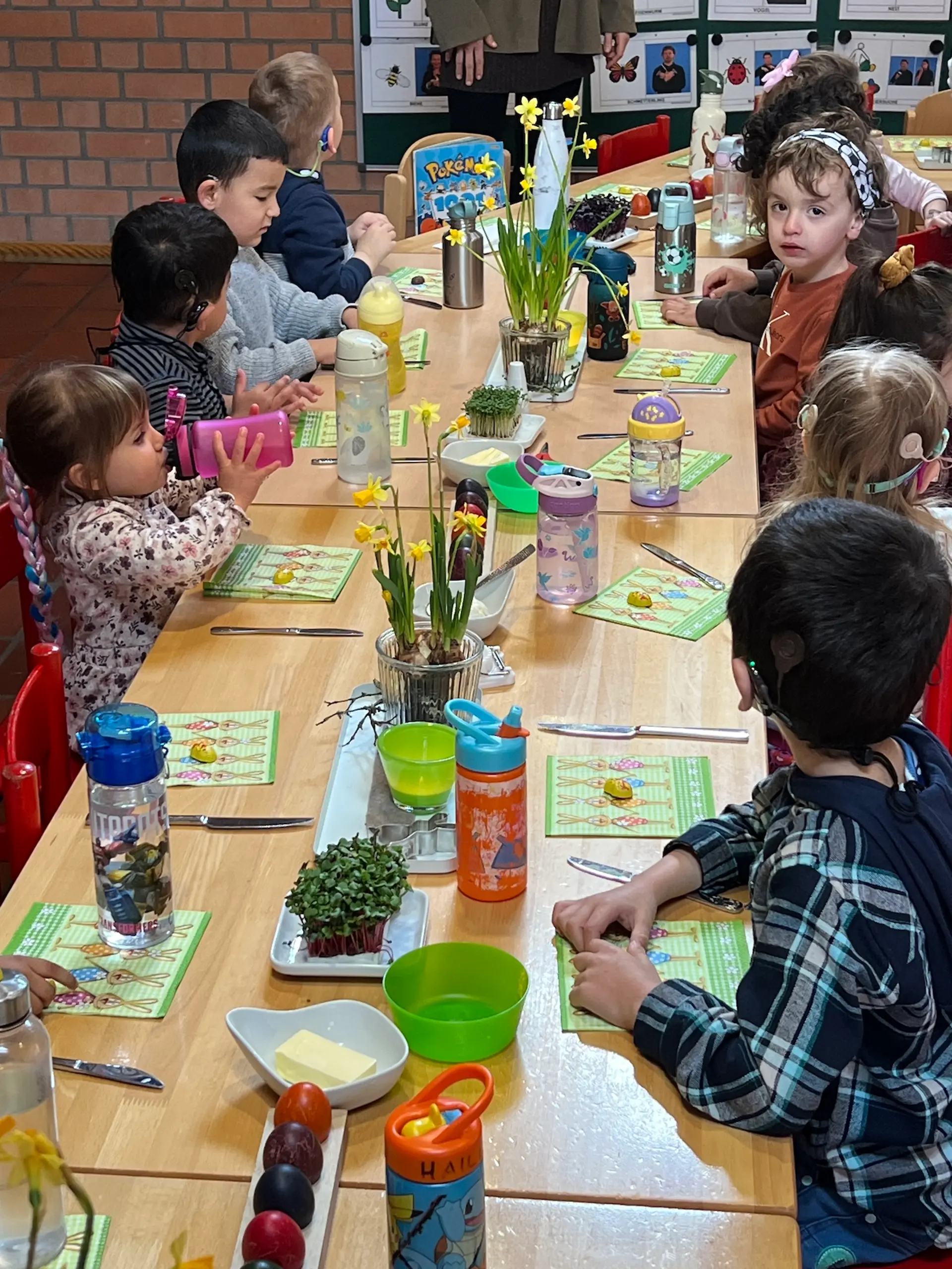 Kinder sitzen an einem langen, österlich gedeckten Tisch