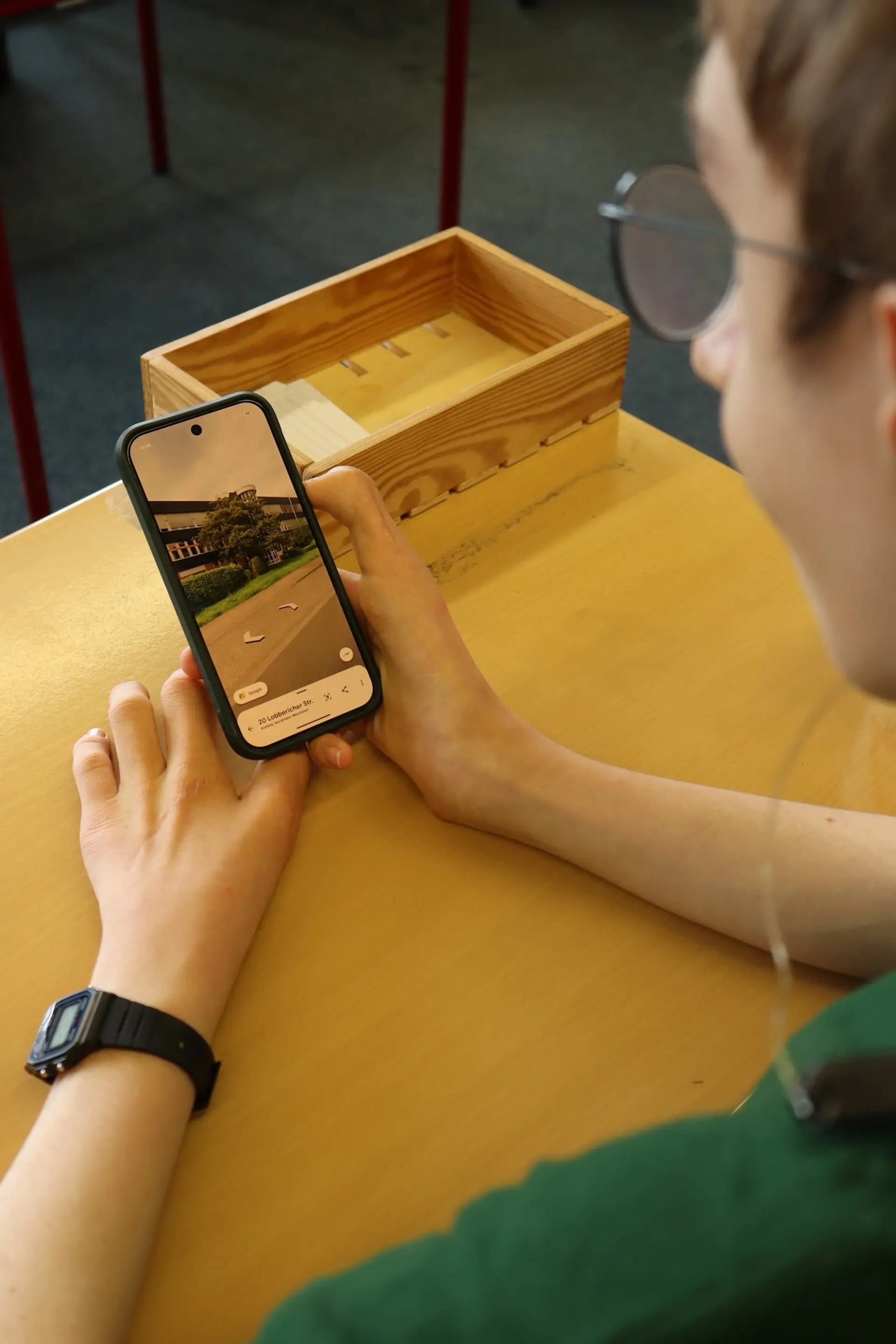 Ein Schüler hält ein Handy mit einer geöffneten Foto-App in der Hand