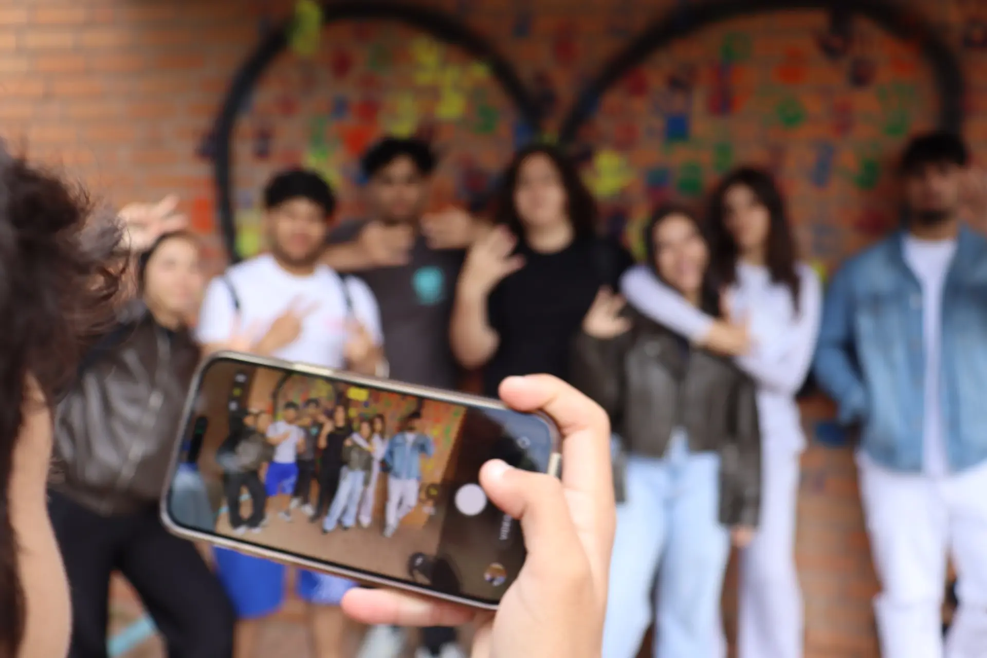 Schüler*innen posieren vor einem Foto-Spot, sie sind alle unscharf gestellt, auf einem Handy-Display sieht man das unscharfe Bild