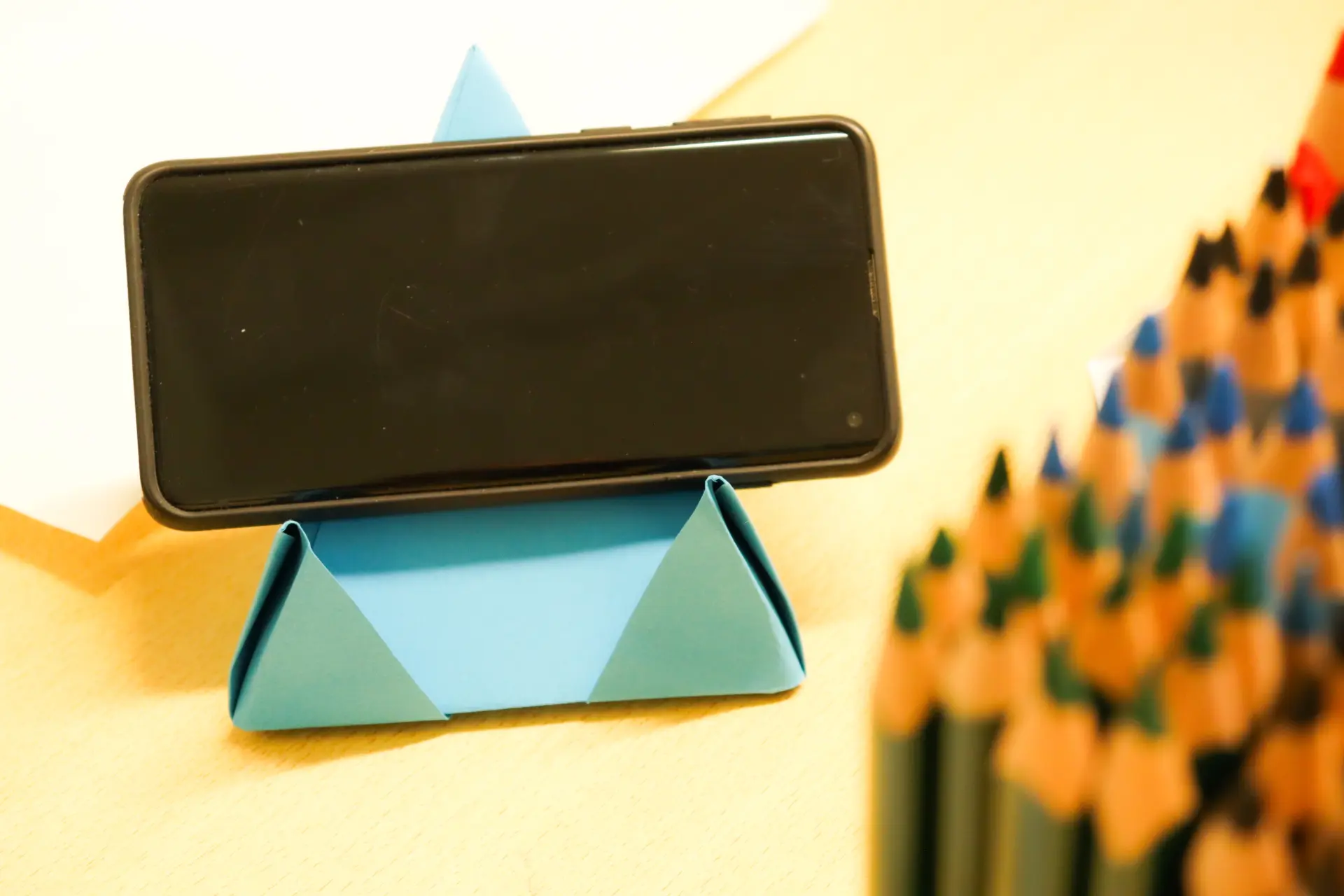 Ein Handy steht in einem selbstgebastelten Handy-Ständer aus Papier