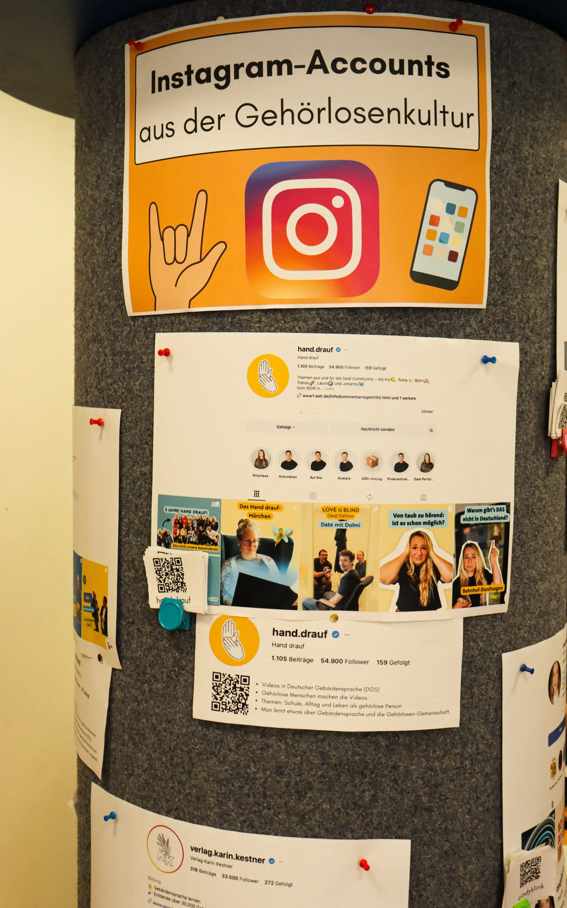 an einer Litfass-Säule hängen Plakate zum Thema "Instagram-Accounts aus der Gehörlosenkultur", zu erkennen ist der Account hand.drauf