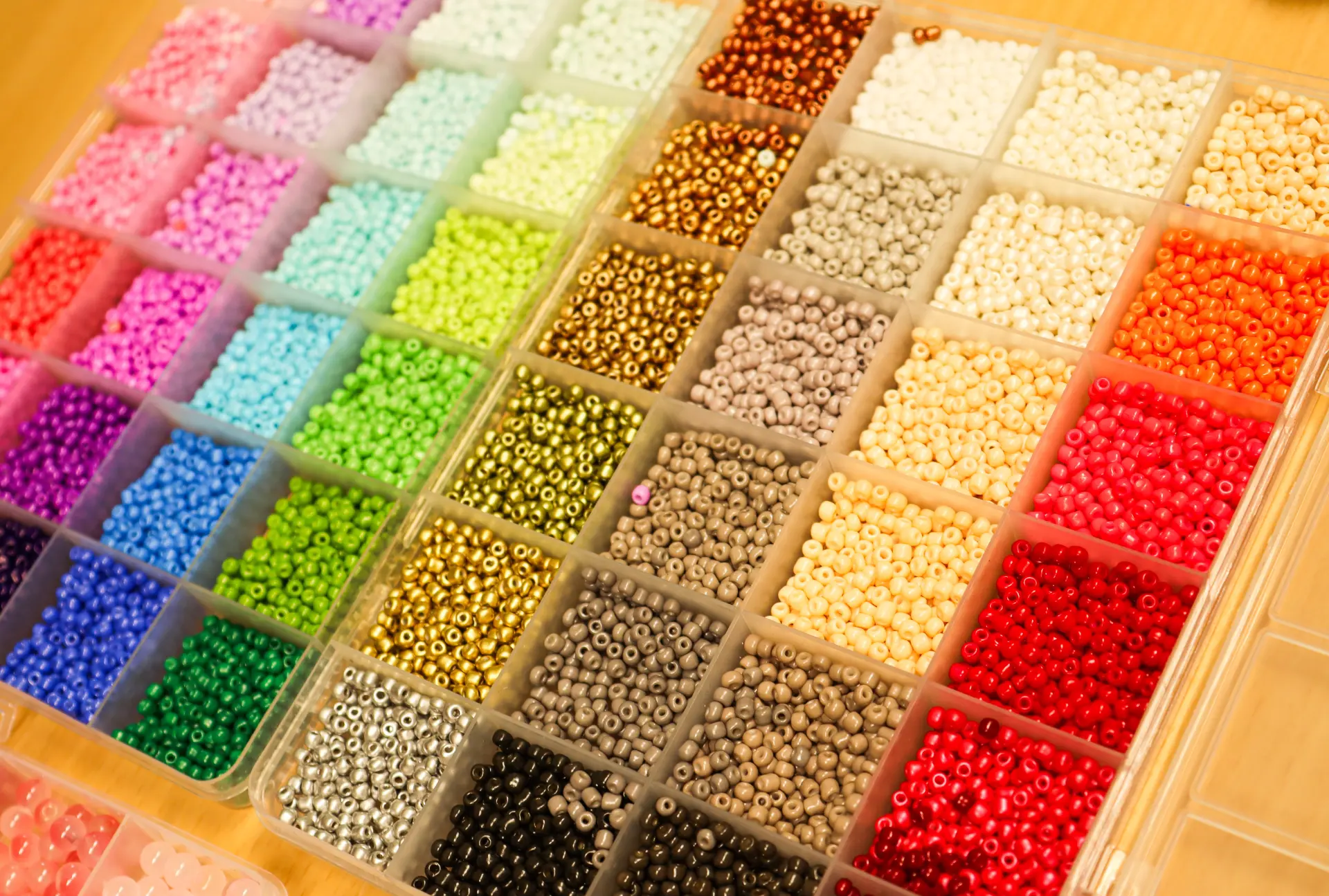 In einem Tableau liegen viele bunte kleine Perlen