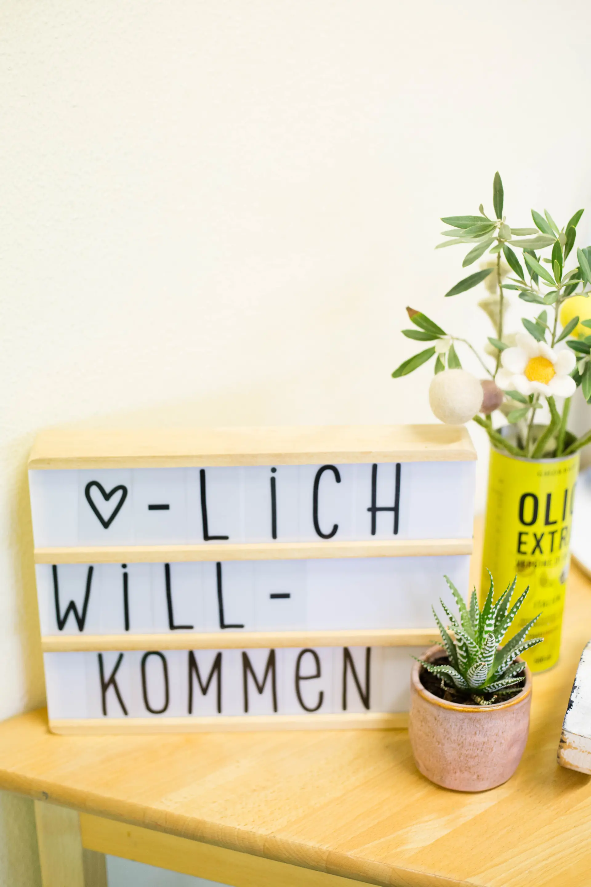Auf einem Tisch stehen Blumen und eine Tafel mit der Aufschrift Herzlich Willkommen
