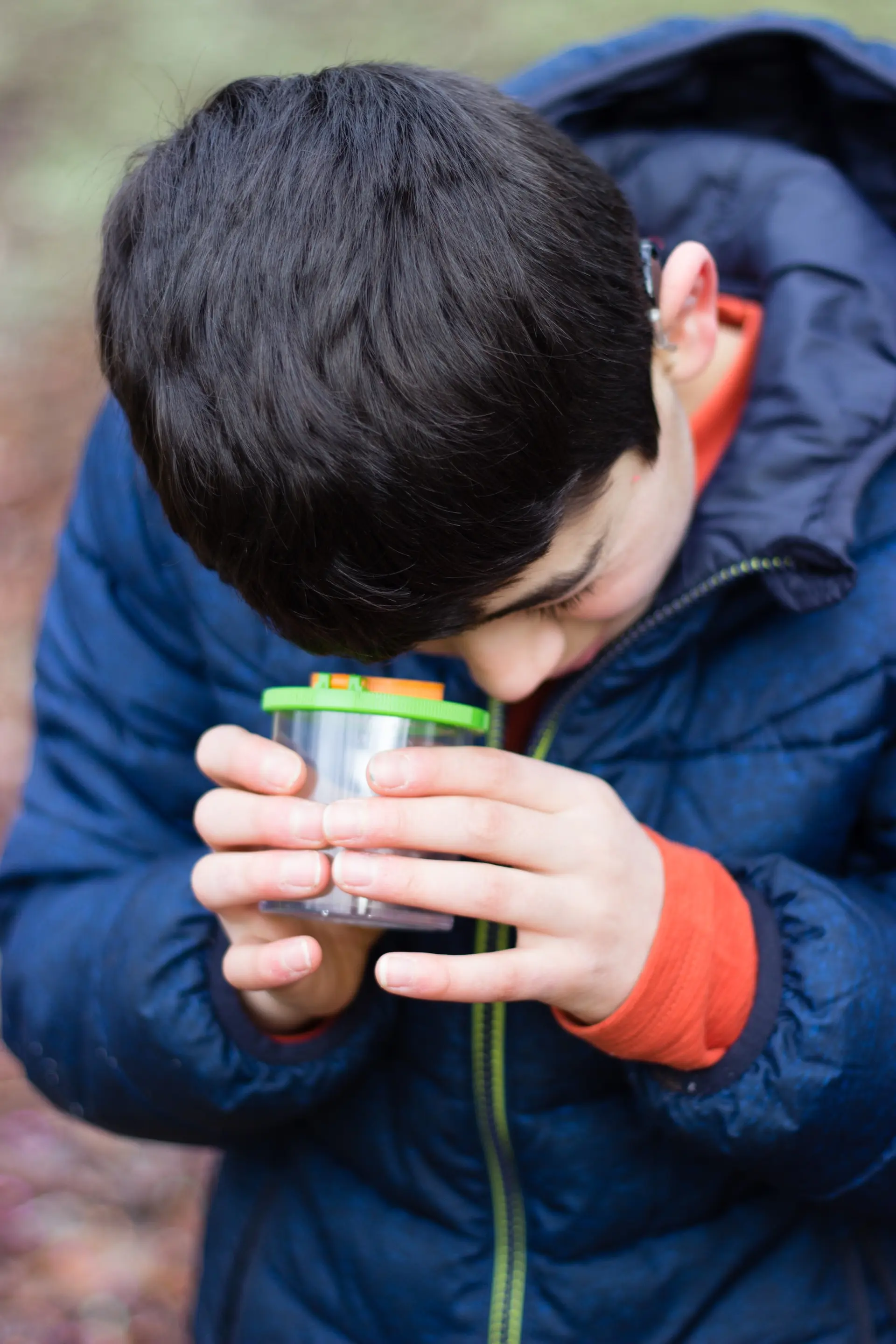Kind untersucht ein Objekt mit einem Lupenglas 