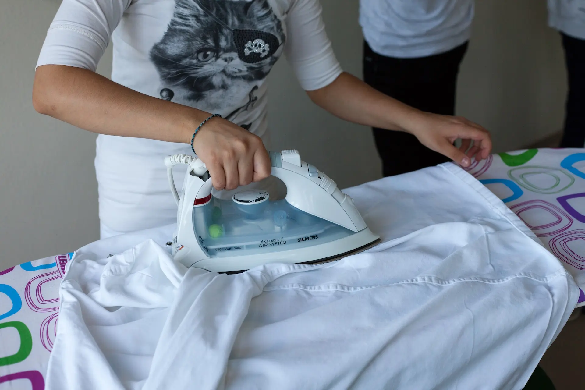 Kind bügelt ein Kleidungsstück für den Second-Hand-Verkauf