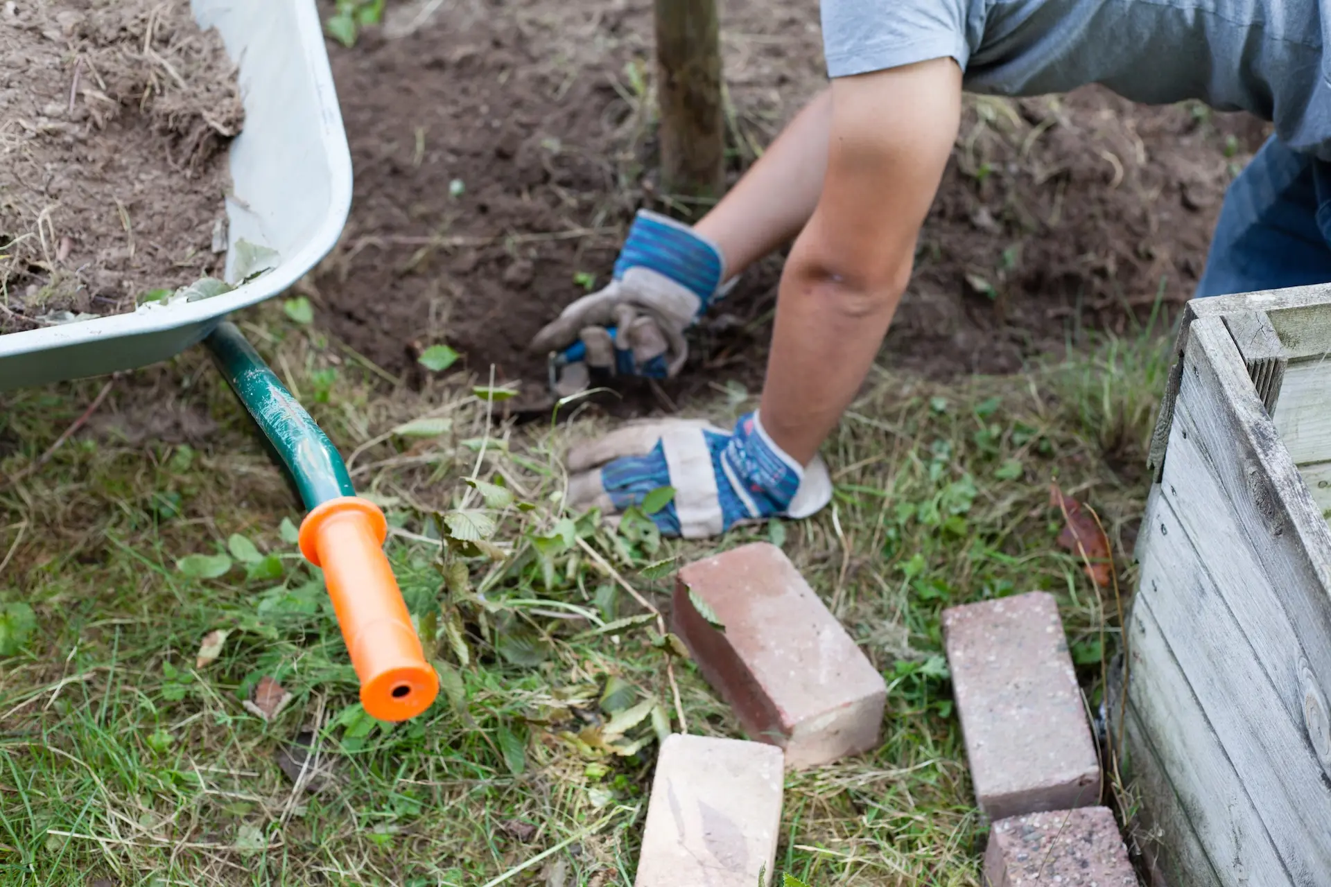 Schüler jätet mit Handschuhen Unkraut im Beet