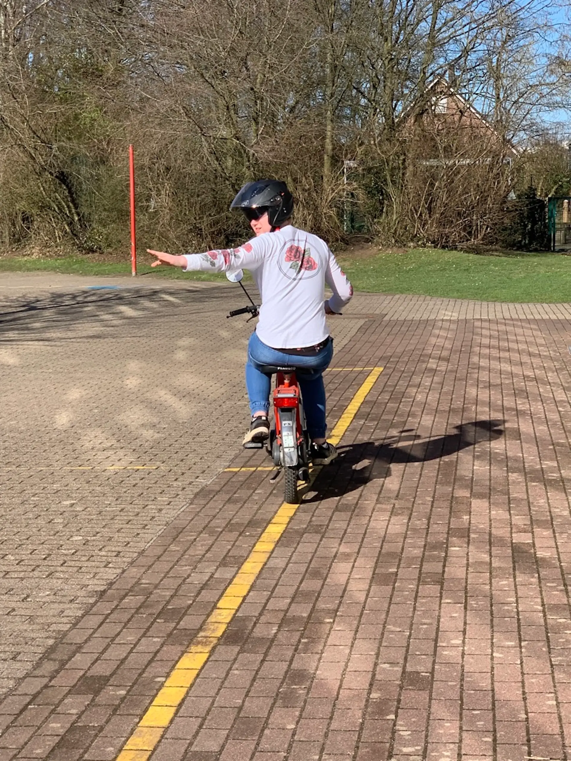 Schüler fährt mit dem Mofa und gibt Handzeichen