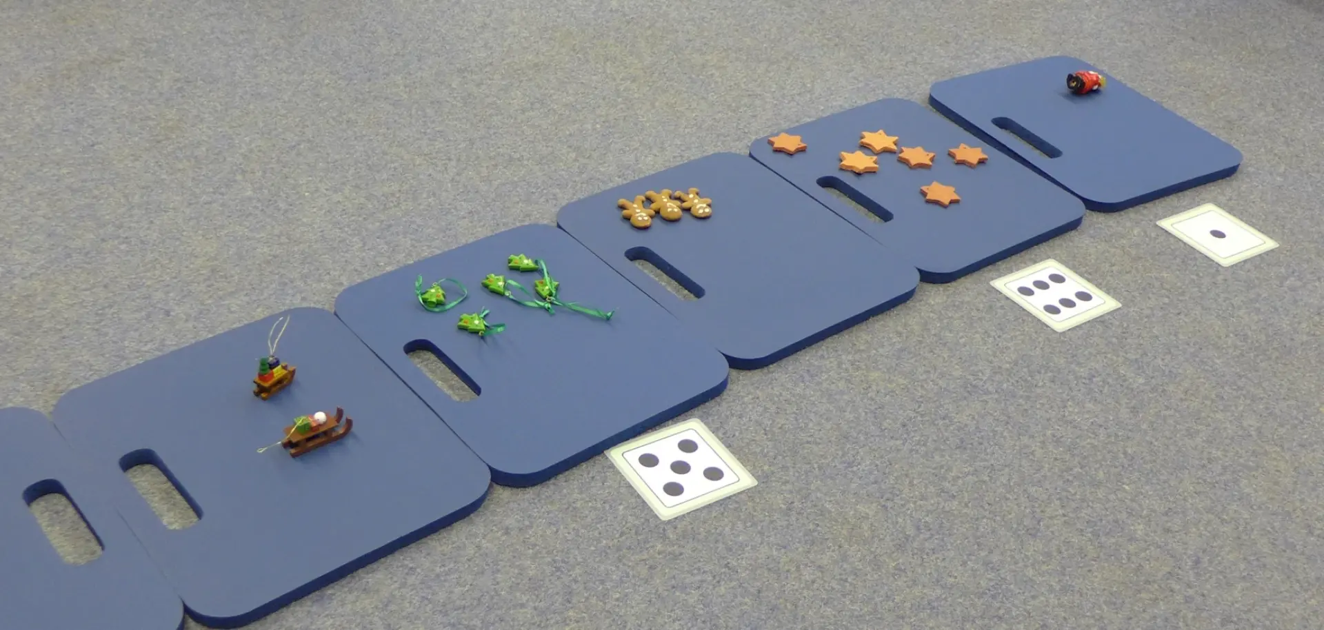 Matten mit verschiedenen Gegenständen in unterschiedlicher Anzahl zur Verdeutlichung der Mengenzuordnung